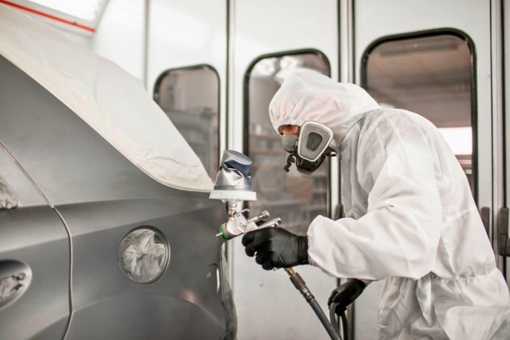 Homme avec un masque qui peint une voiture